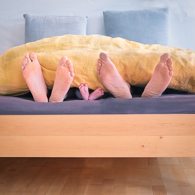 tři páry nohou v posteli